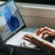 Mani che scrivono su un portatile con Windows 11 appoggiato sulle gambe