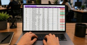 Mani su un portatile che mostra un foglio di calcolo in un ufficio