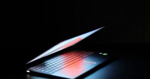 Portatile semiaperto con la tastiera illuminata in una stanza buia