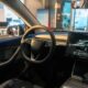 Abitacolo della nuova Tesla Model Y con il volante, la luce ambiente blu e lo schermo centrale acceso