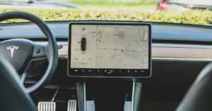 Abitacolo di una Tesla con il volante e lo schermo centrale che mostra la mappa