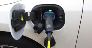 Connettore di ricarica inserito nella presa di un'auto elettrica bianca