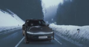 Tesla Model Y Juniper nera su una strada di montagna innevata nella nebbia
