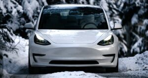 Tesla Model 3 bianca su una strada di montagna innevata