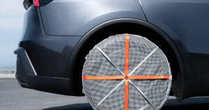 Ruota posteriore di una Tesla Model Y Juniper grigia con una calza da neve in tessuto montata sul pneumatico