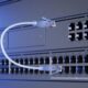 Primo piano di switch UniFi in rack con porte Ethernet e SFP e un cavo di rete bianco, in luce blu