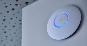 Access point UniFi bianco montato a parete con l'anello LED blu acceso