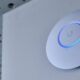 Access point UniFi bianco montato a parete con l'anello LED blu acceso