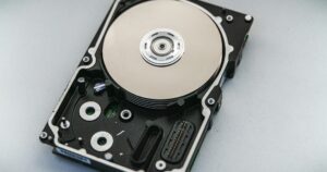 Hard disk aperto con il piatto e la testina in vista su sfondo chiaro
