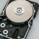 Hard disk aperto con il piatto e la testina in vista su sfondo chiaro