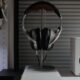 Cuffie over-ear appese a un supporto sulla scrivania accanto a una cassa acustica bianca e al bordo di un monitor