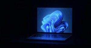 Portatile con lo sfondo blu di Windows 11 acceso in una stanza buia